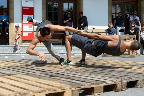 Two men dance acrobatically on wooden palettes