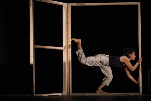 A performer leans into a wooden structure.