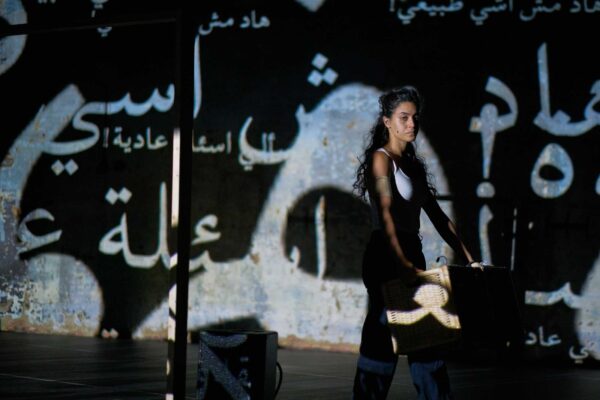 A performer stands in front of projected letters.