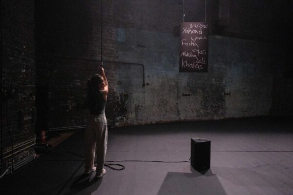 A performer holds a rope, connected to a sign with words written on it.