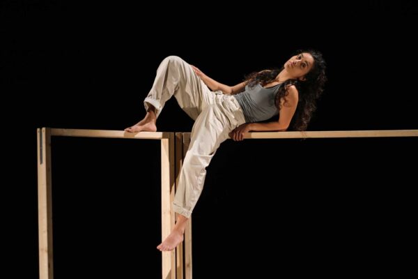 A performer leans back on a wooden structure.