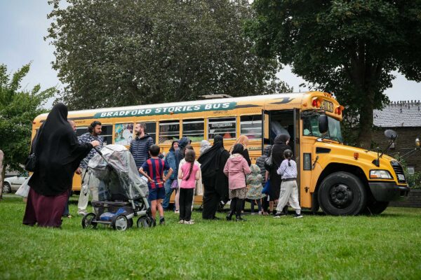 Families queue to get on an old American school bus in a park