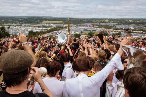 A band play surrounded by a crowd on a hill