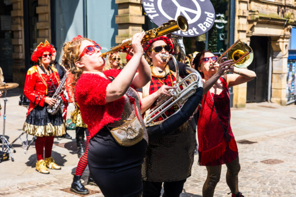 A group of musicians play their instruments in a sunny street