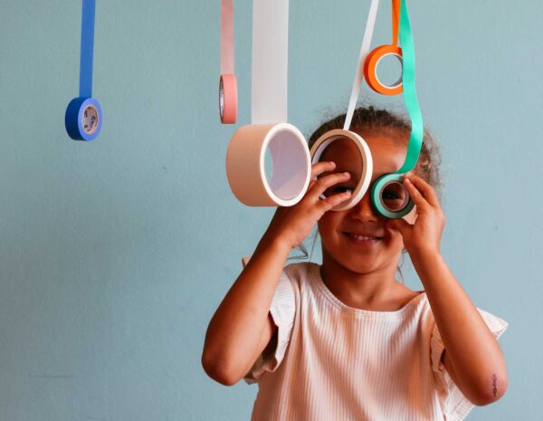 young girl looking through rolls of colourful tape.