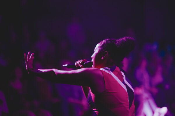 A black woman sings to a crowd.