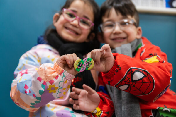 two children smiling holding Bradford2025 badges
