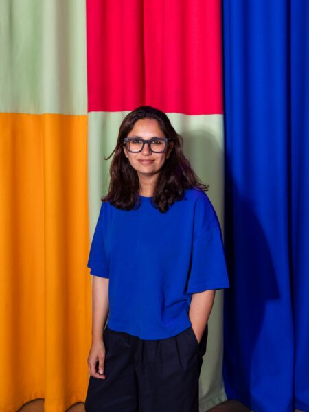 Artist Kangan Infront of colourful curtain she designed