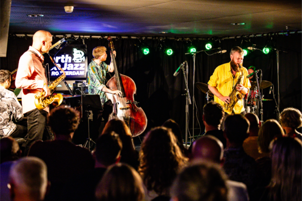 A group of musicians play on stage in front of a crowd.