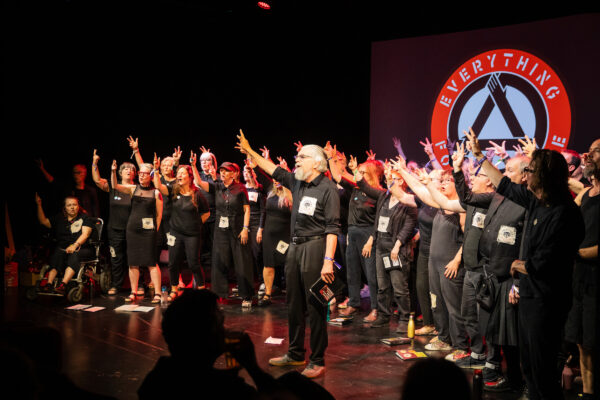 A choir performs on stage, their hands in the air.