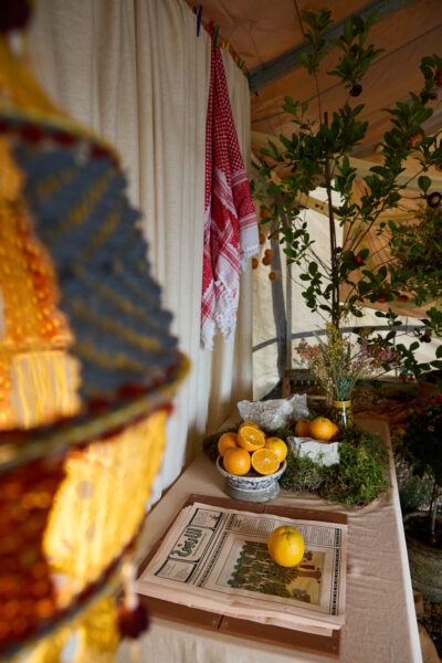 A table with oranges and newspapers sits inside a tent.