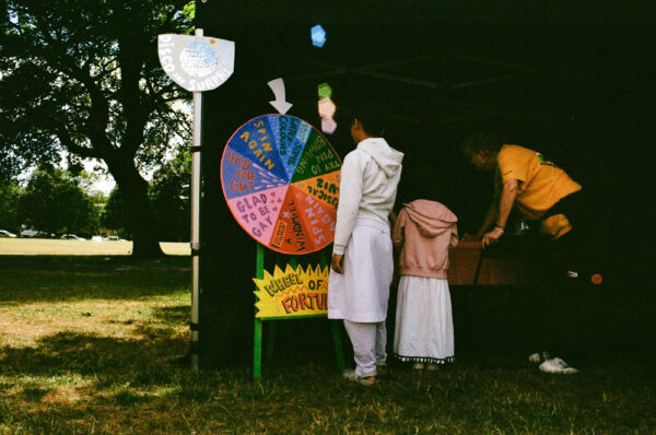 A film photo of a young person spinning a wheel to try and win a prize.