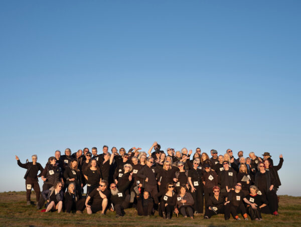 A group of people pose together - with a blue sky behind them.