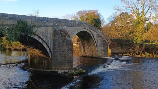 a bridge over a flowing river in ilkley