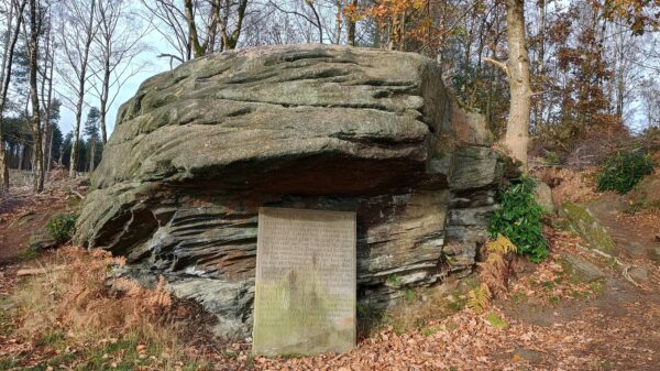 Large rock int he woods, with an engraved headstone infront