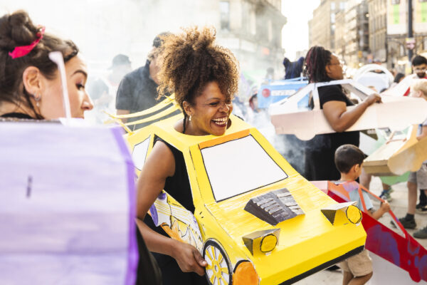 Women who has a yellow cardboard car around her body.