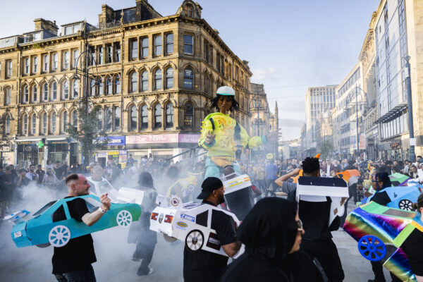 Puppet, Zee and cardboard cars around her in the foreground