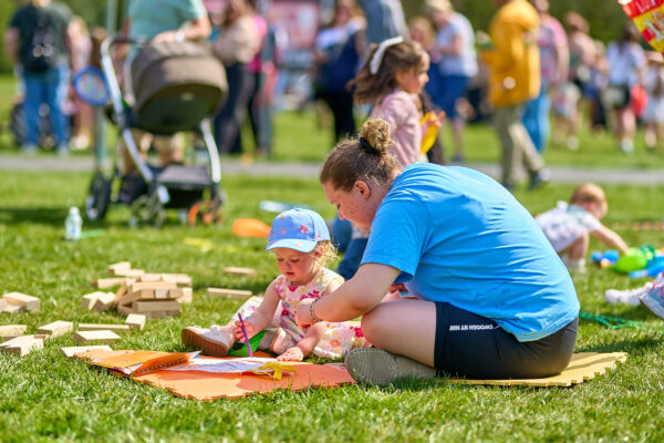 A woman and a young child doing crafts in the park