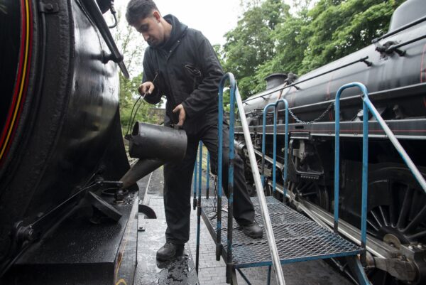 Man pouring something into a steam train