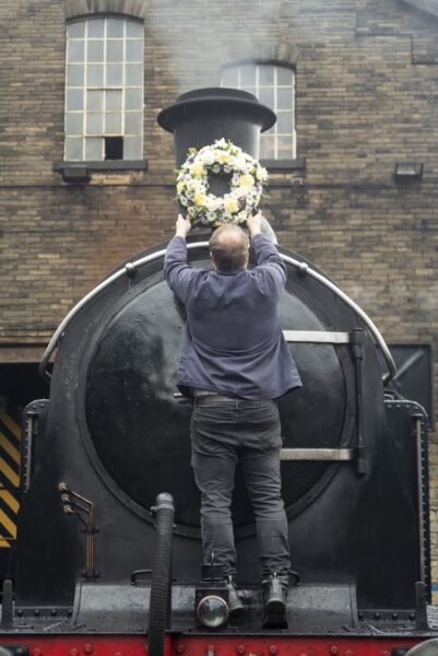 Man putting up wreath onto a steam train