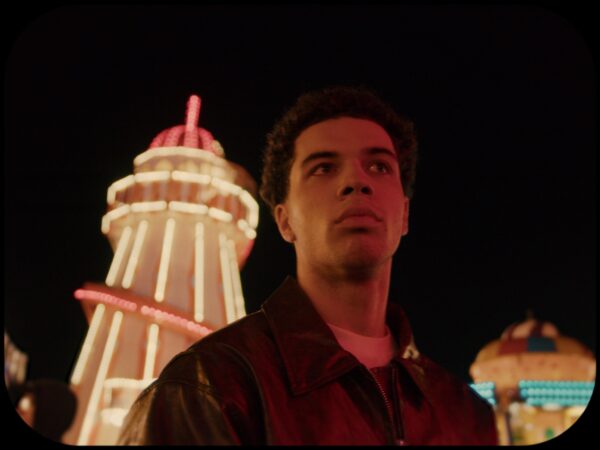 Male stood in foreground with illuminated helter skelter behind them.