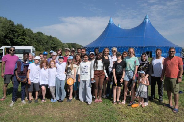 A large group of people stood in a field in front of a circus tent