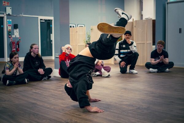 Man doing a break dancing move in the middle of a circle of people