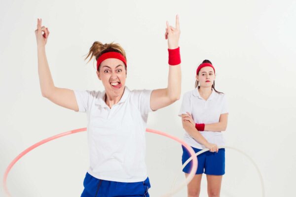 Two women in p.e. kit red wristbands and headbands hula hopp