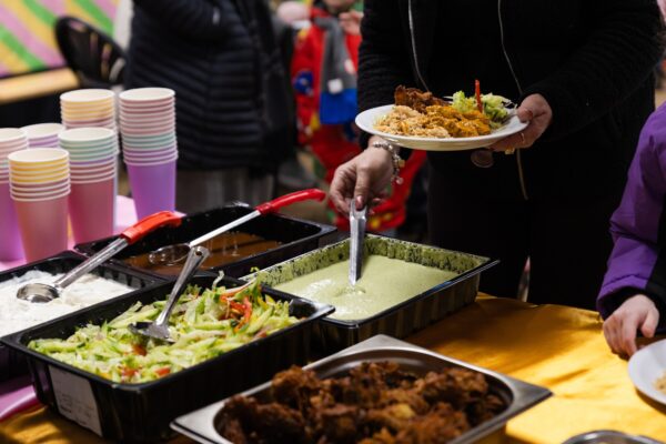 Person spooning out salad, pakoras, samosas