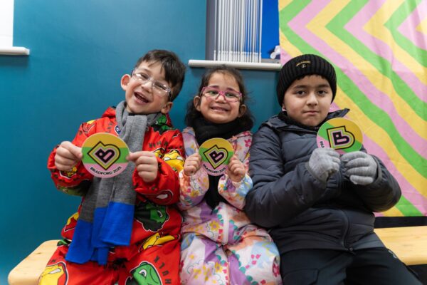 Young children holding up branded Bradford 2025 stickers