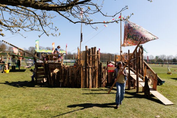 Wooden hand built fort with a flag flying high, placed in a field.