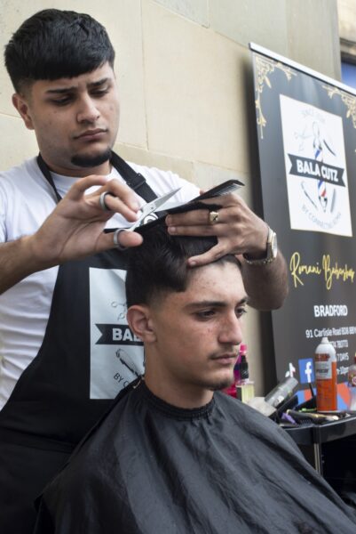 young man cutting another young mans hair outside