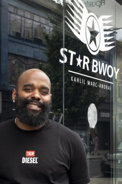 Man smiling infront of shop window, stating 'Star Bwoy