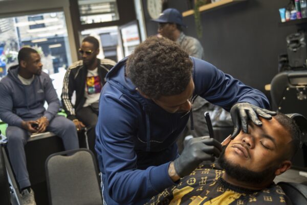 man sat in barbers, getting his beard shaped
