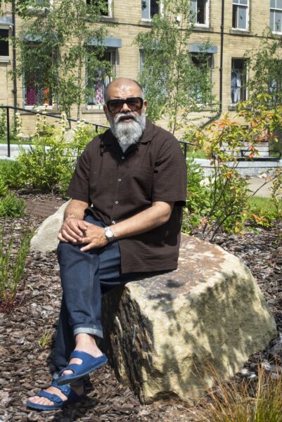 Dipak, radio presenter dat on a large rock posing outdoors