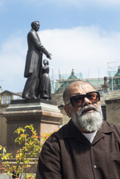 Dipak, radio presenter posing infront of a large statue outside