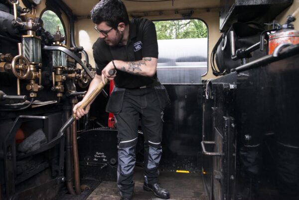 Man shovelling coal into a steam trains engine