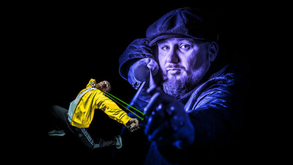 Rapper Big Deli, with a purple coloured filter, holds a slingshot towards us. Next to him is a smaller figure of a person in a tracksuit with yellow jacket, also firing a slingshot.