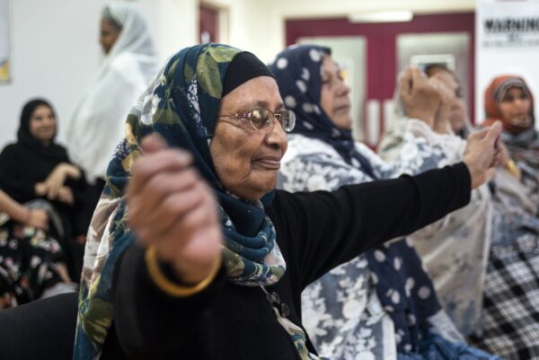 an elderly women in a hijab, with her arms out