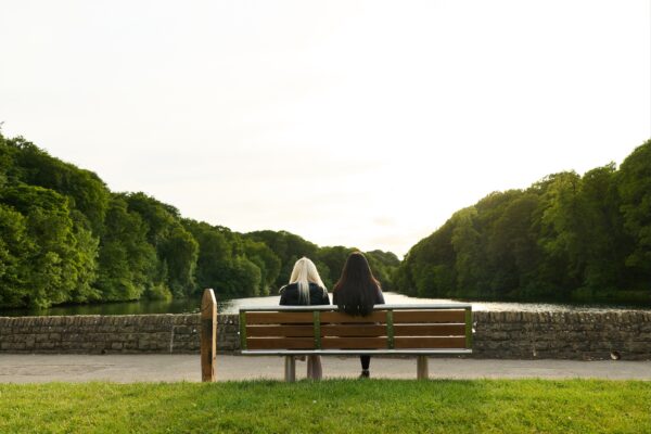 Two girls sat on a bench outside