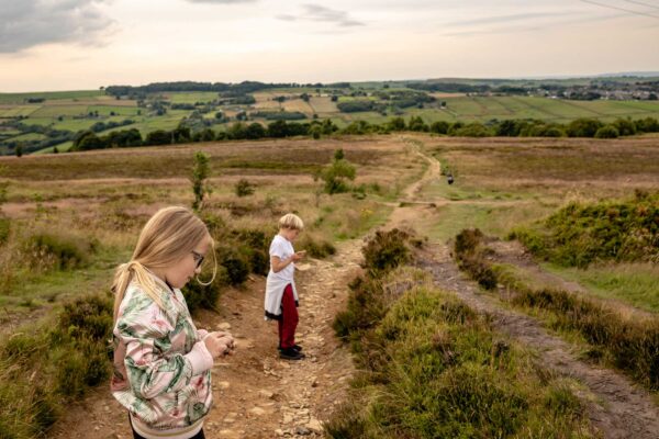 Two children explore a the Bradfordian landscape, with hills and heather.