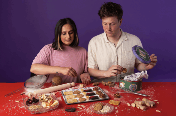 Two people looking at biscuits they've created. Man on right and woman on left.