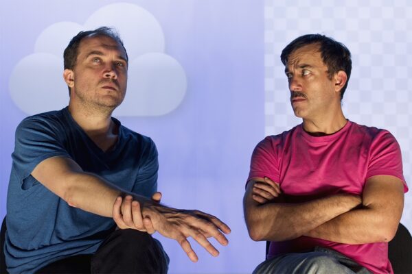 Twi men sat down, one is looking up, the other man sat with his arms crossed