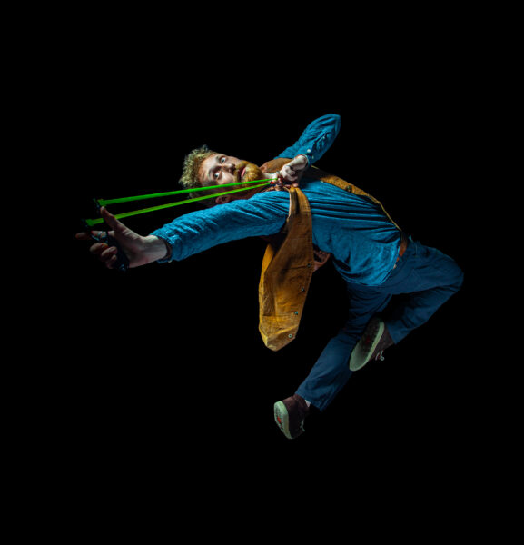 Male jumping in the air with a green slingshot.