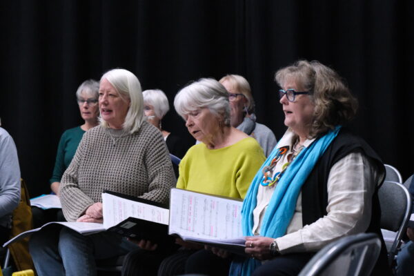 Three women sing in a row.