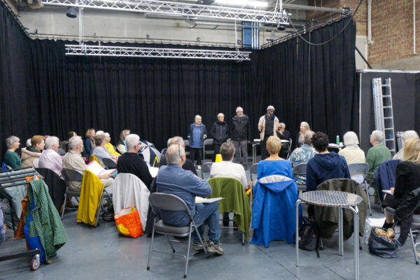 Four men talk to the group.