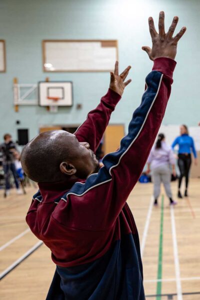 A person raising their hands in the air in a movement workshop.
