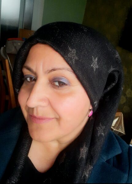 A woman wearing a black headscarf smiles at the camera.