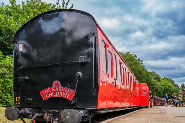 A red and black train carriage with a sign that reads The Railway Children.