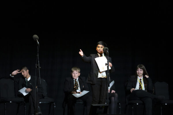 A young boy gestures to the crowd from the stage.